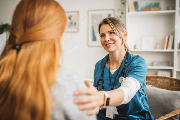 Pflegefachkraft im freundlichen Gespräch mit einer Patientin zu Hause