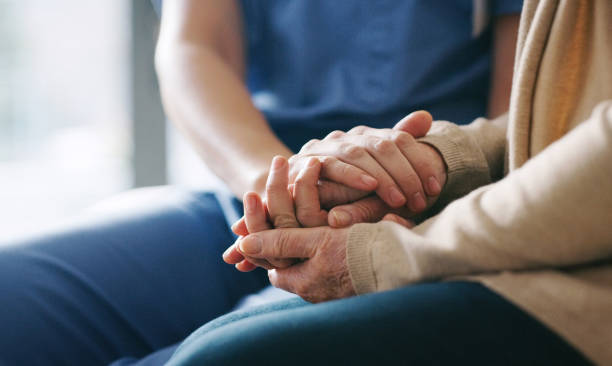 Pflegefachkraft hält die Hände einer älteren Patientin